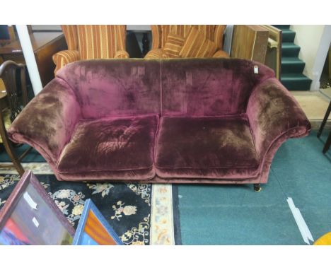 A VELVET UPHOLSTERED TWO SEATER SOFA, the overstuffed back above scrolled arms with loose cushions on turned supports with ca