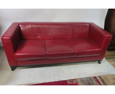 A 20TH CENTURY RED LEATHER UPHOLSTERED THREE SEATER SOFA, of rectangular form with close upholstered back seat and side on wo