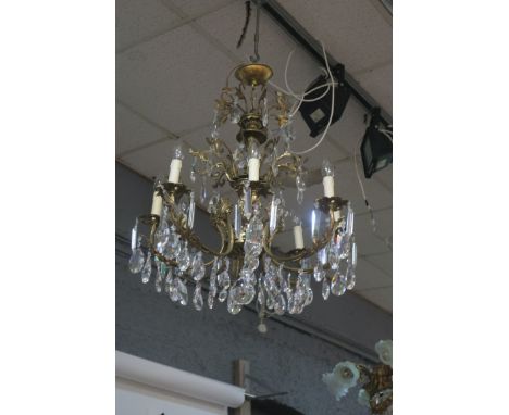 A CONTINENTAL STYLE GILT BRASS EIGHT LIGHT CHANDELIER, the foliate scrolled frame with pierced drip pans hung with pendent dr