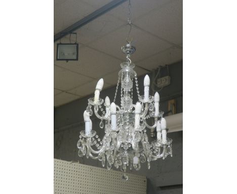 A 12 LIGHT CUT GLASS HANGING CHANDELIER, the diamond cut waisted stem issuing scrolled arms headed by foliate drip pans hung 