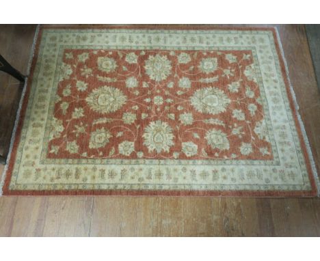 A WOOL RUG, the light pink and beige ground with central floral panel within a conforming border 108cms x 128cms