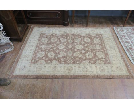 A WOOL RUG, the light brown and beige field with central floral panel within a conforming border 270cms x 155cms