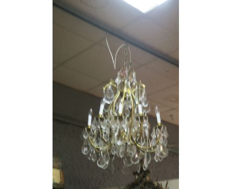 A CONTINENTAL STYLE TEN LIGHT CHANDELIER, the scrolled arms above foliate shaped drip pans hung with pendent drops.