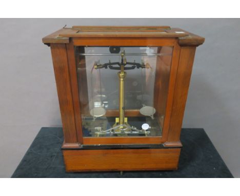 AN EDWARDIAN MAHOGANY CASED WEIGHING SCALES, the glazed sides revealing a brass column fitted with silver plates above the ba