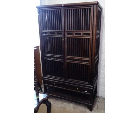 An Oriental design hardwood 2-section cabinet, with turned spindle panels and 2 doors, with drawers under and shelf below, W1