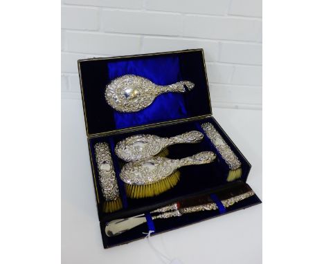 Victorian silver backed vanity set , chased with cherub and floral pattern, comprising mirror, two hairbrushes, two clothes b