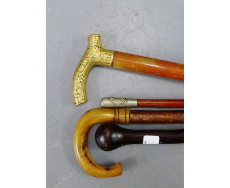 A collection of walking sticks to include a horn handled example, one with brass handle, another with faux ivory dogs head ha