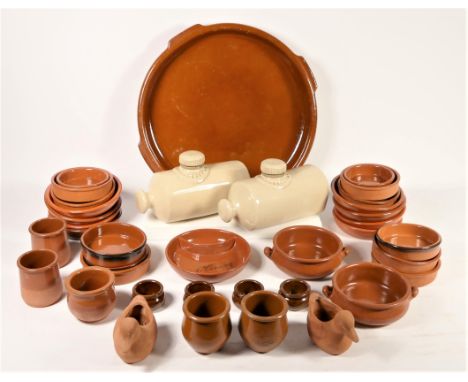 A collection of glazed terracotta dinner/oven ware, together with early 20th Century stoneware hot bottles, an Eccles miners 