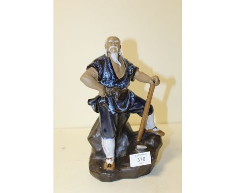 AN ORIENTAL CERAMIC FIGURE OF A MAN WITH AN AXE