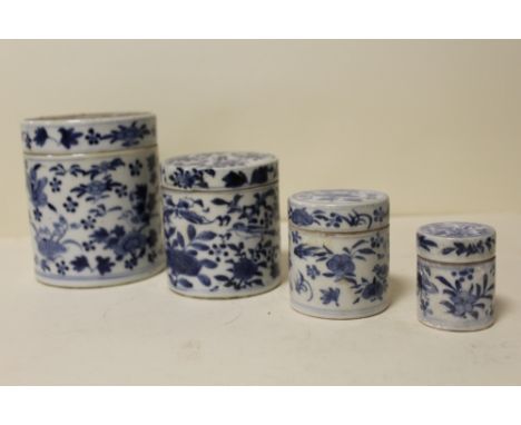 AN ORIENTAL SET OF FOUR GRADUATED BLUE AND WHITE CERAMIC CYLINDRICAL LIDDED POTS 
