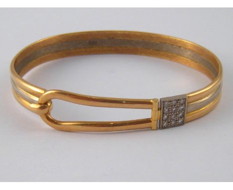 A yellow and white metal (tests 18 carat gold) diamond set bangle, designed as a buckle, internal width approx 6.3cm, 35.2 gm