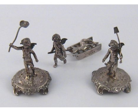 Miniatures. A cherub drawing a sled carrying a deer, import marks for 1901, and two cherubs on stands, one with net, the othe