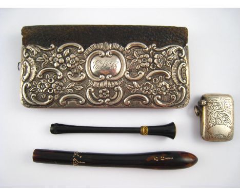 A mixed lot. A lady's wallet with embossed silver cover, a silver vesta, a faux tortoiseshell lorgnette handle and a long cig