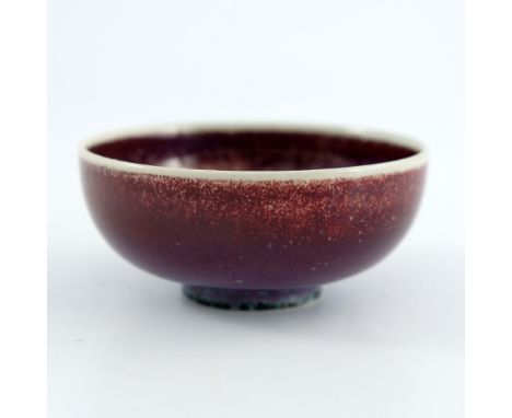 Ruskin Pottery, a small High Fired bowl, circa 1915, rounded form, ox blood draining to purple glaze with green spotted foot 