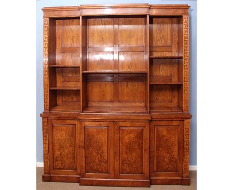 Burr oak library bookcase of break front form, the upper section with fitted adjustable shelving over base with cupboards on 