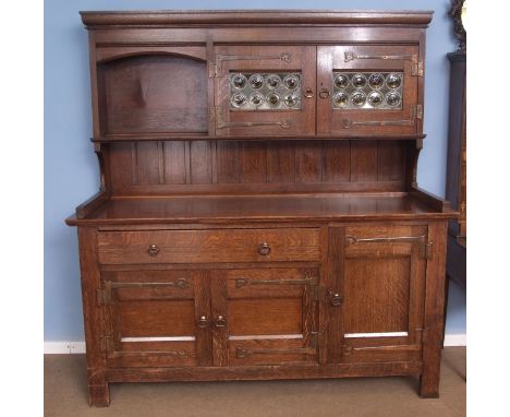 A Liberty &amp; Co oak dresser, (marked with ivorine plaque inside drawer), the pediment with two leaded glazed doors beside 