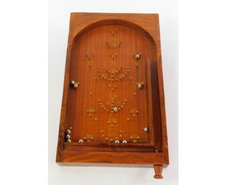 A wooden table top bagatelle, with balls.