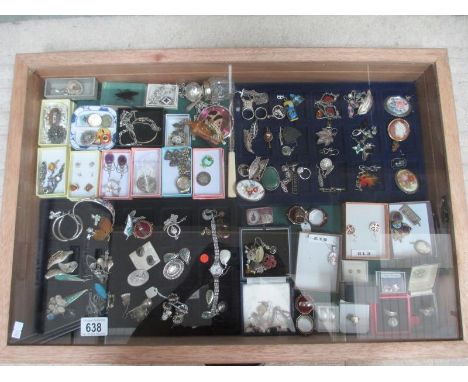 A display case containing in excess of 100 pieces of mainly silver jewellery including earrings, pendants, rings etc, badges 