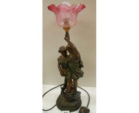 A bronzed effect figure group table lamp with cranberry glass shade.