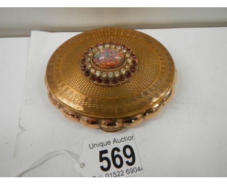 A 1950's oval powder compact with jeweled top, in good condition.