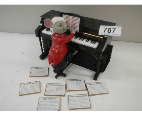 A battery operated mouse playing a piano with 7 tune sheets that are inserted in the back for him to play.
