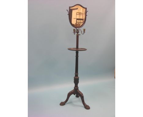 An early 20th century mahogany dressing stand, shield-shape mirror above pair of brass candle-arms, stem with dished, circula