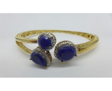 A silver gilt bangle set with blue stones and diamonds