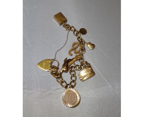 A gold charm bracelet with various charms to inc lighter, dolphin, notes, guitar