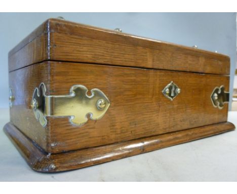 An Edwardian light oak cigar box with decoratively overlaid and rivetted brass mounts, having straight sides and a hinged lid