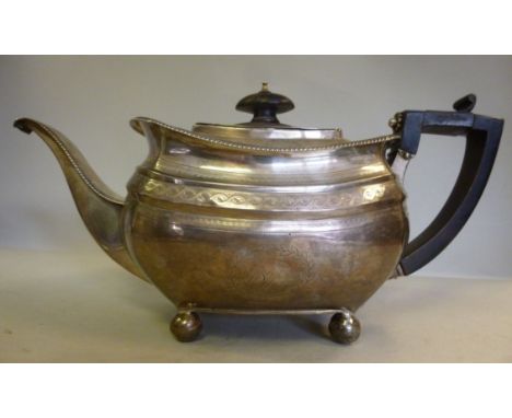 A George III silver teapot of bulbous, panelled form, having a swept spout, an ebonised handgrip and knop to the flush fittin