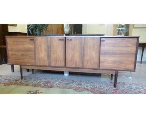 A 1960s Christian Linneberg design, rosewood sideboard, the two central sliding doors enclosing three green baise lined and o