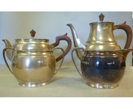 A four piece silver tea set of oval, bulbous form  comprising a teapot having a swept spout, a curved wooden handgrip and kno