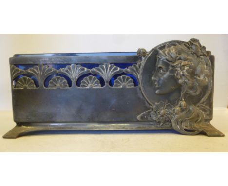 An Art Nouveau Britannia metal planter with a blue glass liner, decorated with profile portraits of young women and stylised 