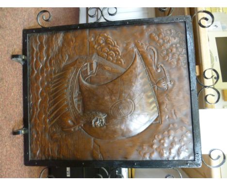 An early 20thC Arts & Crafts black painted wrought iron framed firescreen, set with a patinated, beaten copper panel, featuri