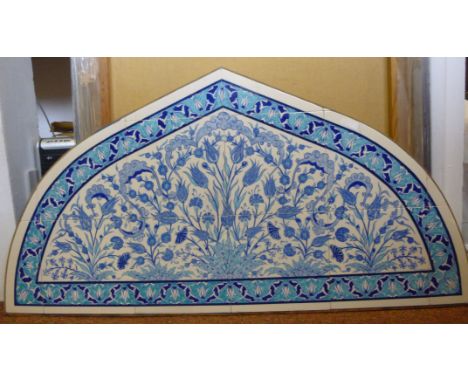 F Zehra - a pointed arched panel of ceramic tiles, decorated in tones of blue and turquoise with flowers and foliage within a