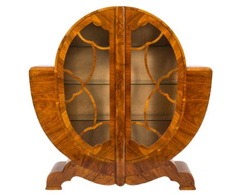 An Art Deco walnut veneer display cabinet:, of circular form, fitted with plate glass shelves and enclosed by a pair of glaze