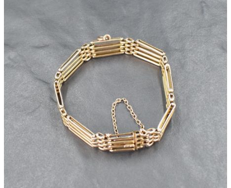 A yellow metal four bar gate bracelet marked 9ct, having a loop attachment and safety chain, approximately 16.5cm internal ci