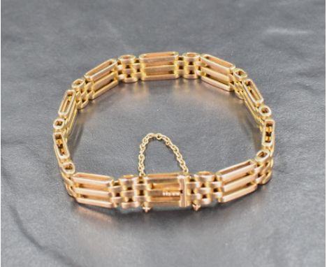 A yellow metal three bar gate bracelet marked 15, having a safety chain to clasp, approximately 17cm internal circumference a