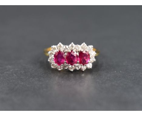 A ruby and diamond cluster ring, the three oval cut rubies measuring approximately 0.20 each with an eighteen round cut diamo