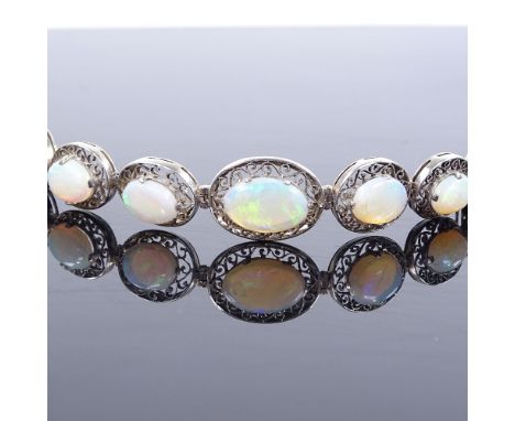 An unmarked white metal graduated cabochon opal panel bracelet, with pierced scrollwork settings, bracelet length 18.5cm, 11.