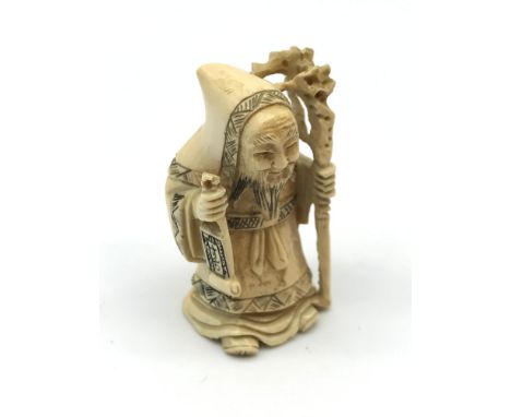 A 19th century Japanese hand carved netsuke figure, Old man holding a scroll and walking stick, signed to the base, Measures 