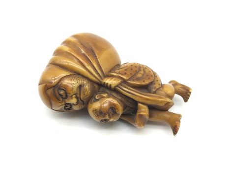 A 19th century hand carved Japanese netsuke, Man carrying a large faced figure, Signed to the base of the robe, Measures 5cm 