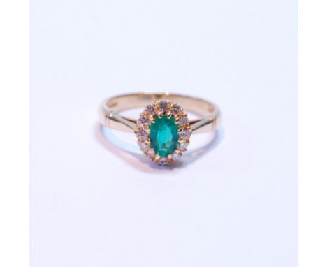 Diamond and emerald oval cluster ring, the emerald approximately 5mm x 4mm, and small diamond brilliants, in 18ct yellow gold