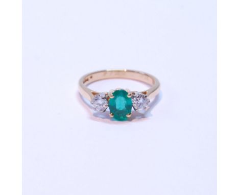 Diamond and emerald three-stone ring, the oval emerald approximately .72mm x 5mm, between two brilliants, each approximately 