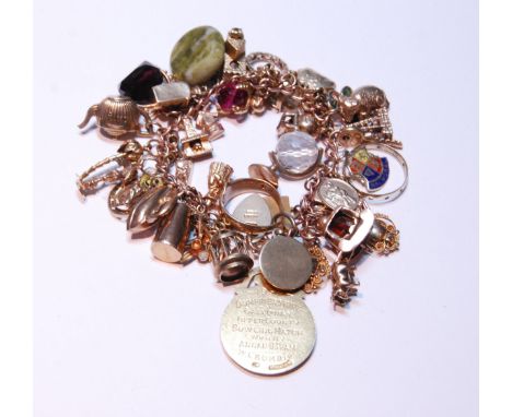 9ct gold charm bracelet with multiple charms and gems dependant to include a medal, ring, fob, pendants, most stamped, 83.9g 