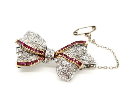 Ruby and diamond set bow brooch in 18ct white gold. With 33 yellow gold channel set baguette rubies and 56 diamonds - 4cm acr