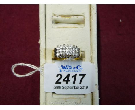 A yellow metal ring set with twenty small simulated diamonds and a simulated seed pearl, size "S" approx.