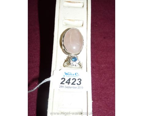 An unhallmarked white metal ring set with an oval pink rose quartz stone, ring size "O", and a silver metal cluster ring mark