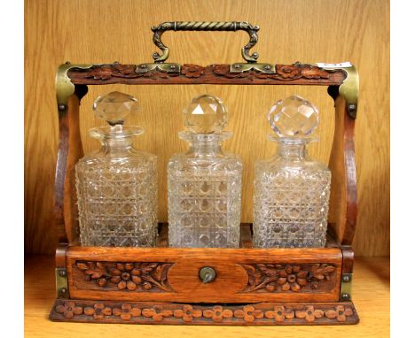 A carved oak three bottle tantalus, W. 36cm, H. 35cm.