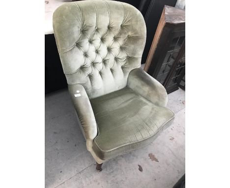 A BUTTON BACK FABRIC ARMCHAIR ON MAHOGANY SUPPORTS WITH BRASS CASTERS 